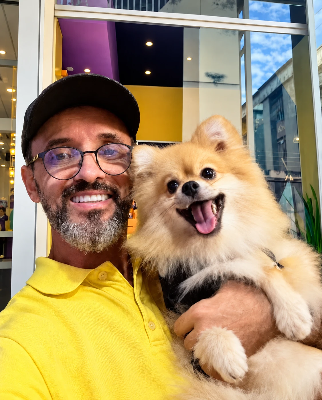 Dono da Dom Pet Shop sorridente segurando um spitz-alemão fofo